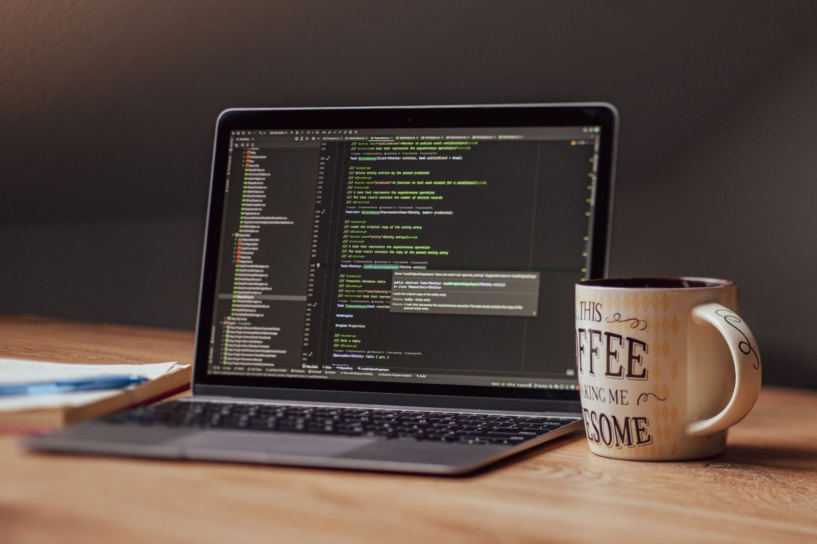 Laptop displaying code editor with coffee mug on desk, perfect for tech themes.