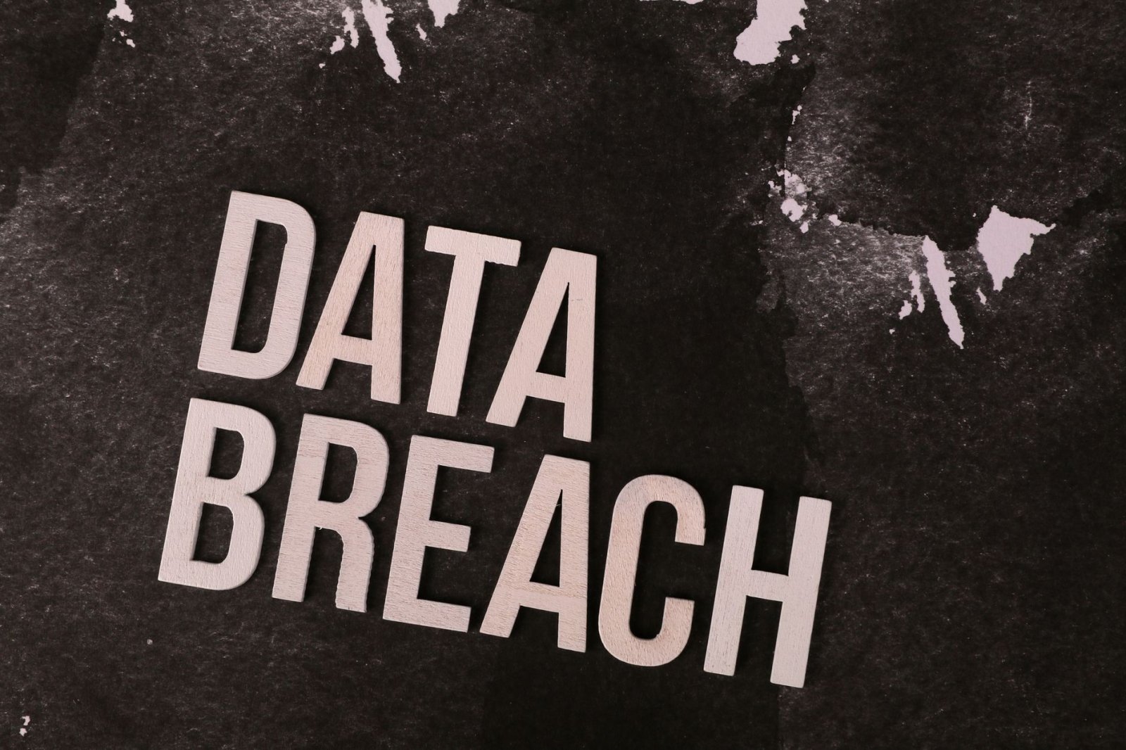 A conceptual image highlighting the issue of data breaches, featuring bold text on a textured background.
