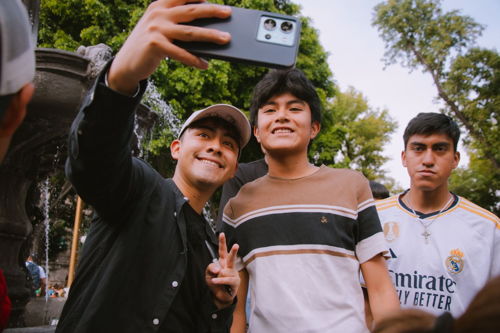 Three young men enjoying a selfie outside. Vibrant smiles and casual attire in an outdoor setting.