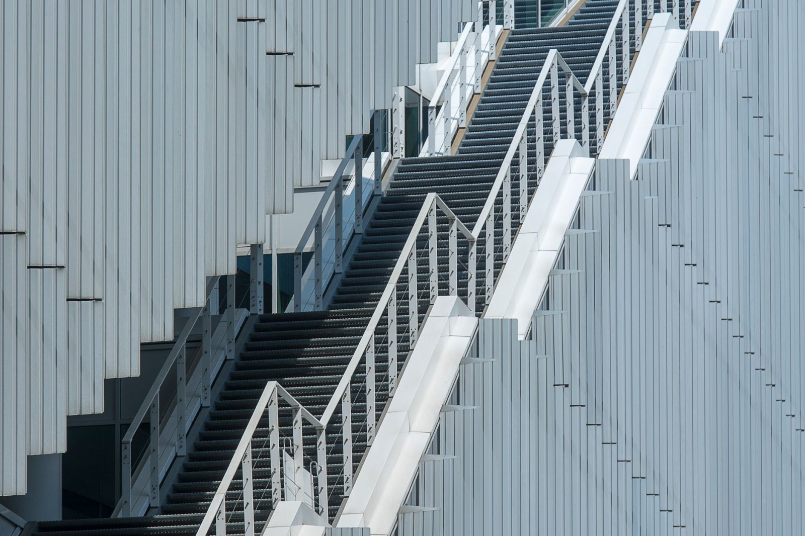 Sleek metal staircase against a modern building facade in an urban environment.