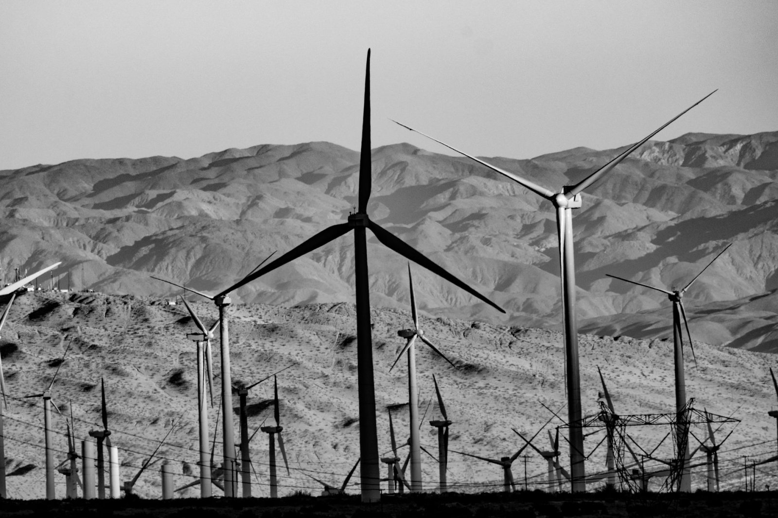 Black and white image of wind turbines against desert mountains in Cabazon, CA, highlighting renewable energy.