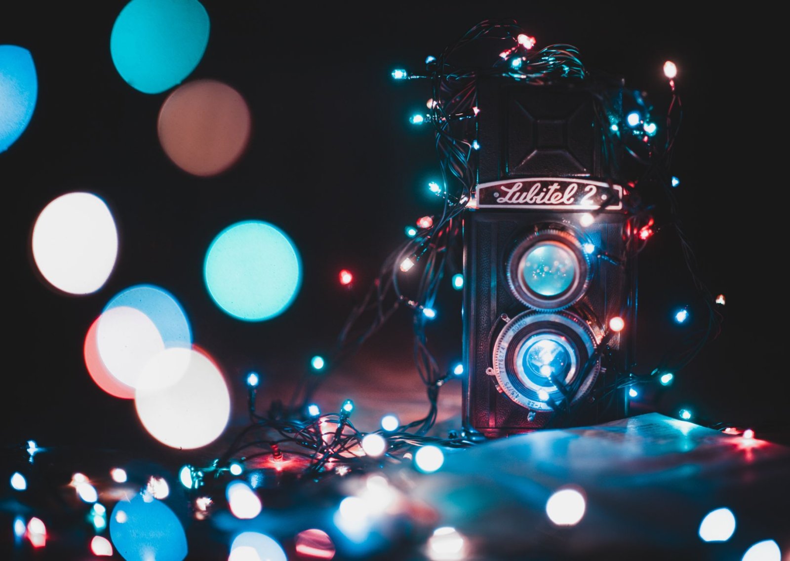 A vintage Lubitel 2 camera surrounded by colorful bokeh string lights, creating a festive atmosphere.