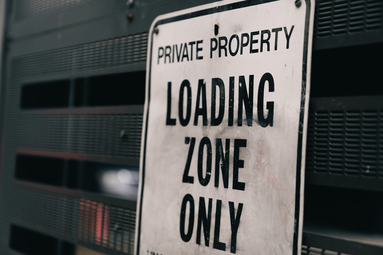 Close-up of a private property loading zone only sign with urban backdrop.